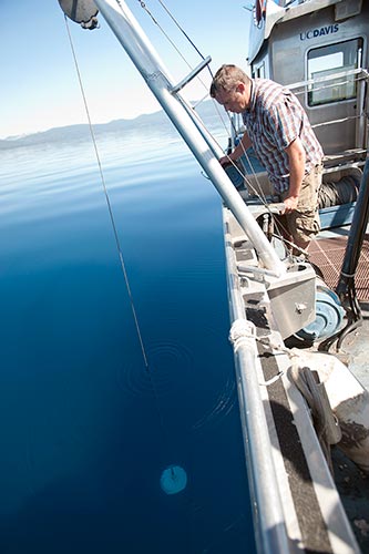 Research Associate Raph Townsend drops a Secchi disk and marks the depth when the disk disappears to check water clarity at Lake Tahoe, California. The UC Davis Tahoe Environmental Research Center does testing, monitoring, and conservation on the lake. (Photo credit: Gregory Urquiaga | UC Davis)