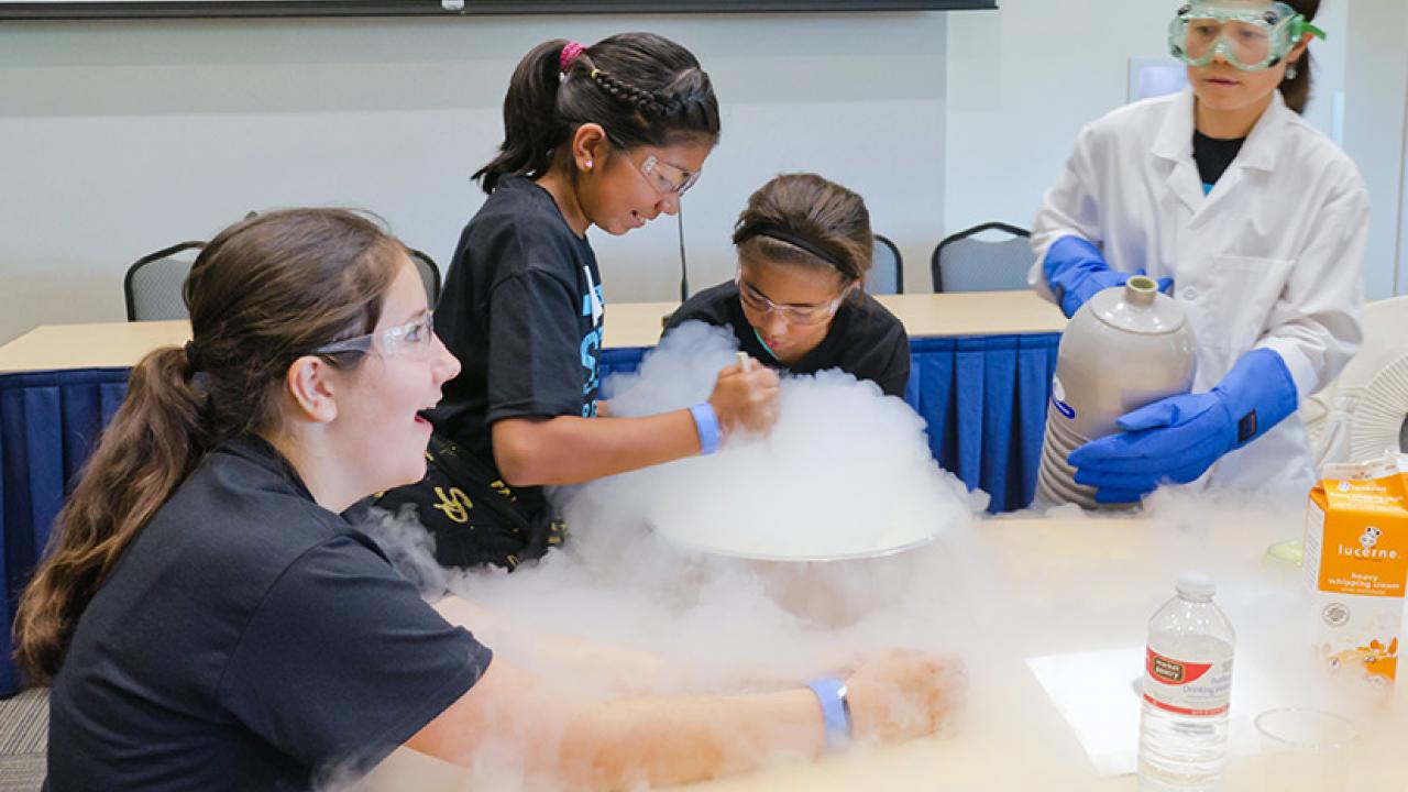 Biological and agricultural engineering professor Tina Jeoh (right) pours liquid nitrogen into a mixture of cream, sugar, and vanilla to make ice cream, an activity designed to stimulate interest in science.
