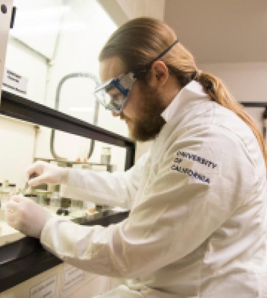 A male researcher uses a fume hood in the lab.